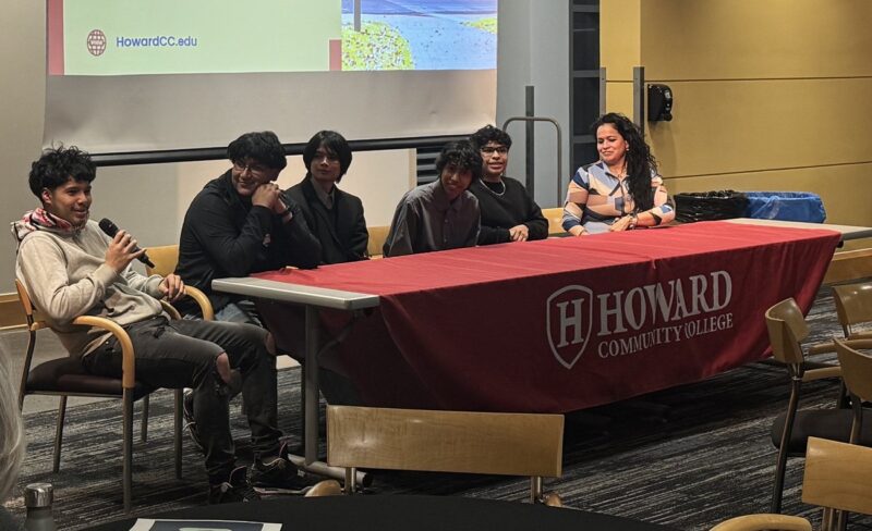 OhanaHC students seated at a panel discussion at Howard Community College, with a Dragon Country presentation on the screen behind them.
