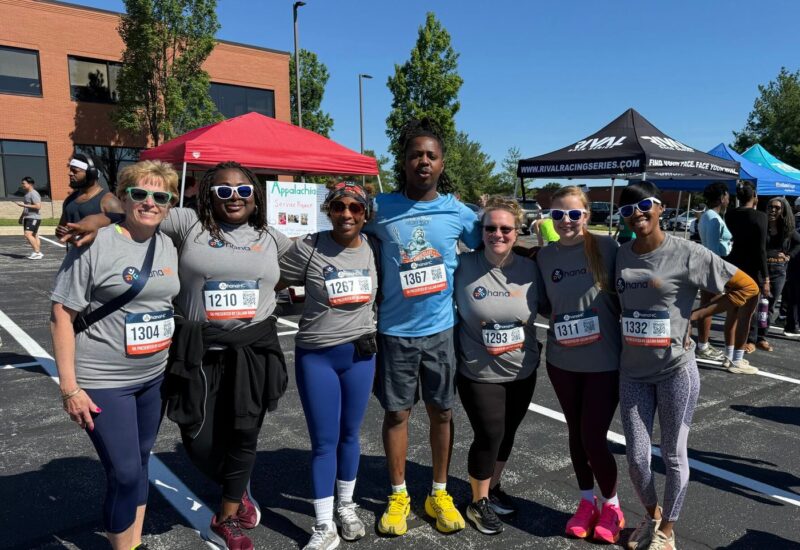 A large group of OhanaHC participants outdoors in matching shirts and race numbers at a community fundraising event.