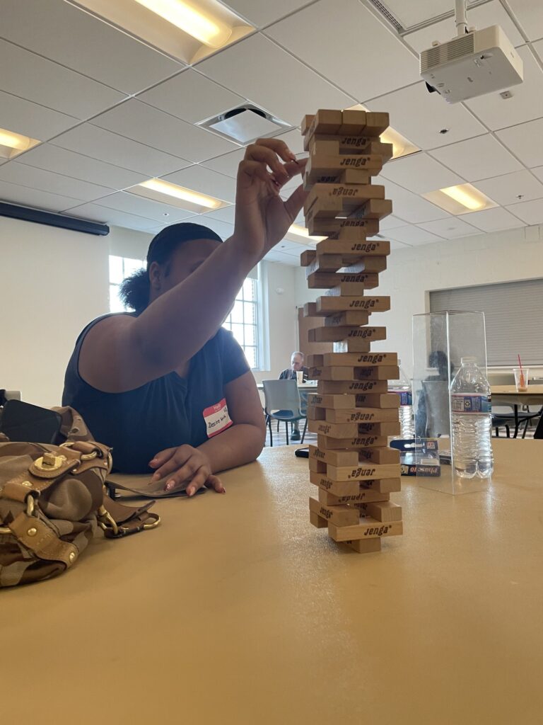A student steadying a very tall Jenga tower at an OhanaHC game night