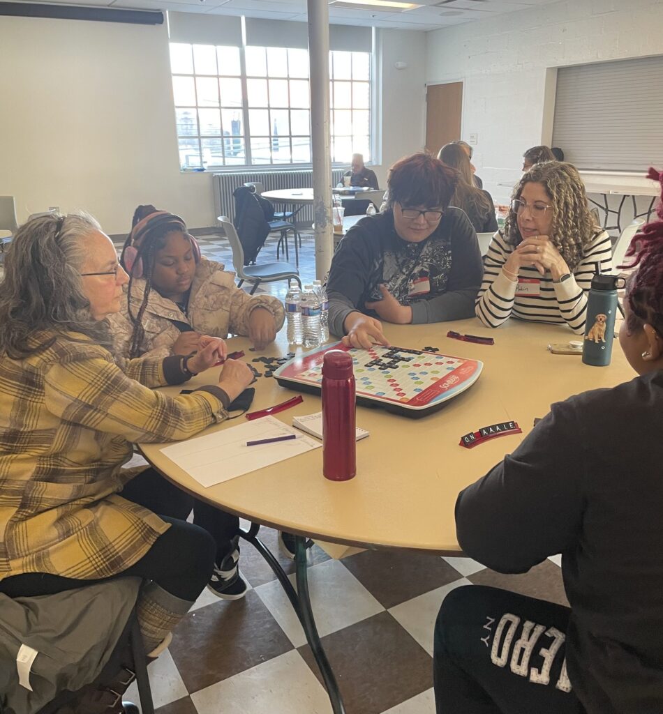 Students and mentors playing Scrabble around a table