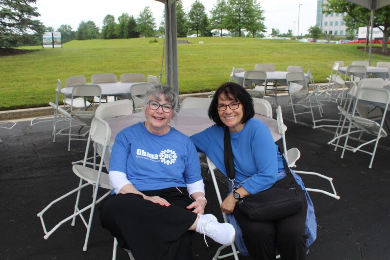 Two OhanaHC volunteers in OhanaHC shirts sitting together at the 5K