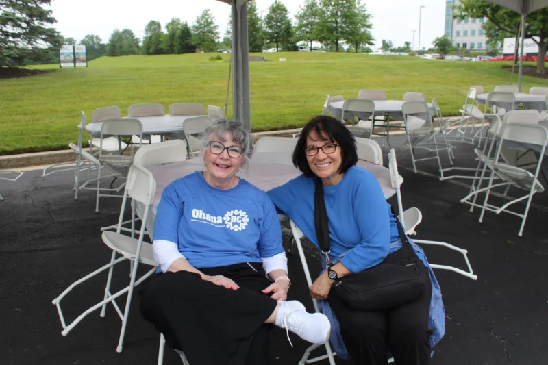 Two OhanaHC volunteers in OhanaHC shirts sitting together at the 5K