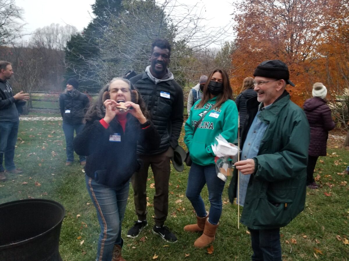 OhanaHC mentors and students gathered outside around a fire pit on an autumn afternoon.