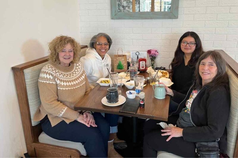 Mentors and a student sharing breakfast together in a diner booth