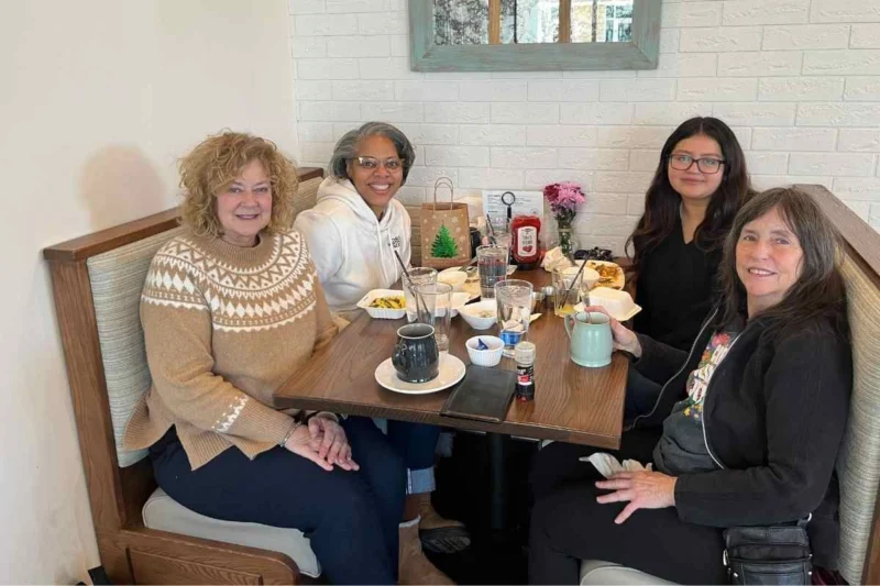 Mentors and a student sharing breakfast together in a diner booth
