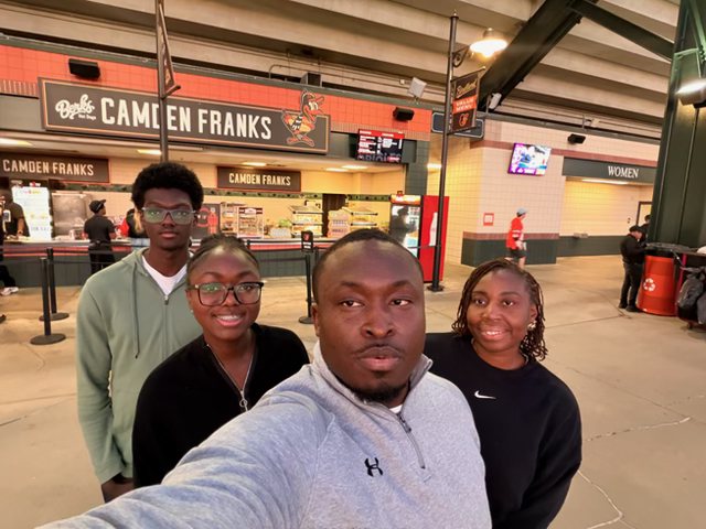 A mentor and three students at the ballpark, taking a photograph together