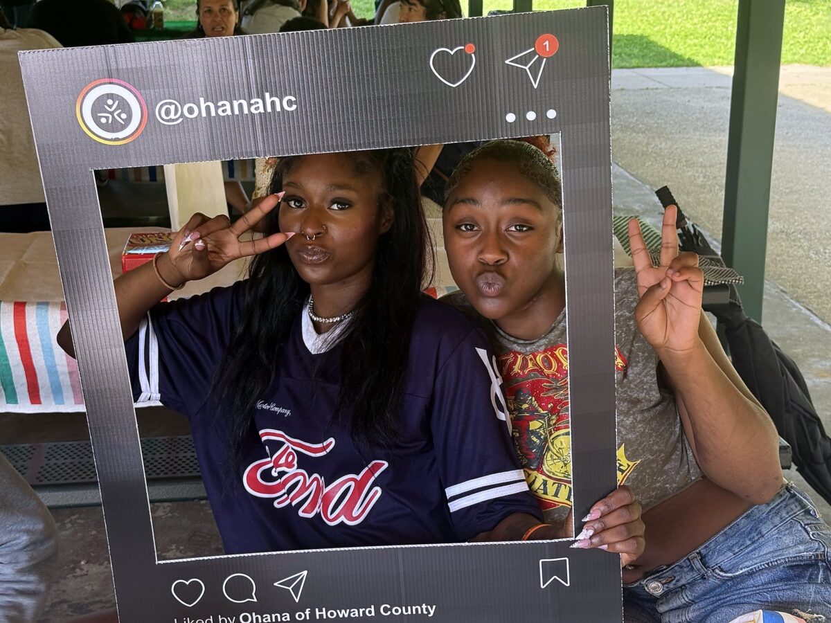 Two OhanaHC students holding up an OhanaHC photo frame together at a community event