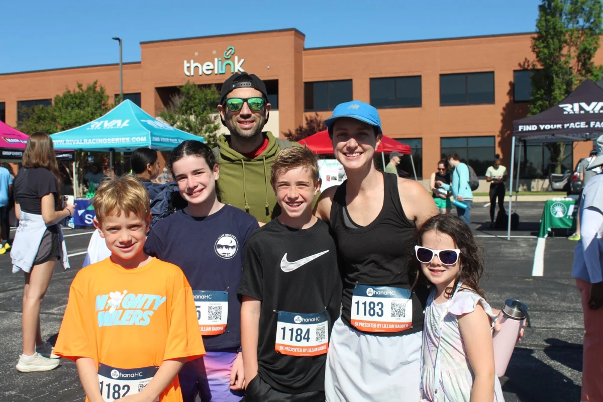 A family team in race bibs, three children and two adults, smiling together at the Ohana 5K.