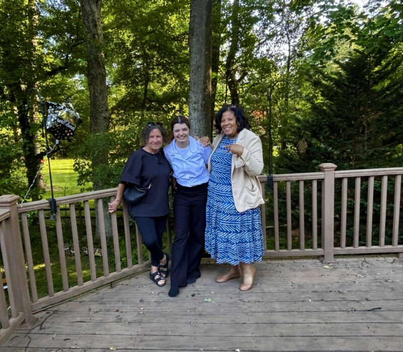 Aradia with two women from her Ohana on a backyard deck, celebrating her graduation