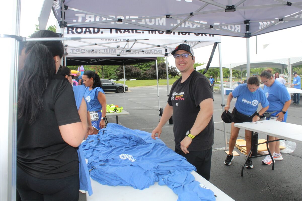 OhanaHC volunteers laying out shirts for runners at a registration tent.
