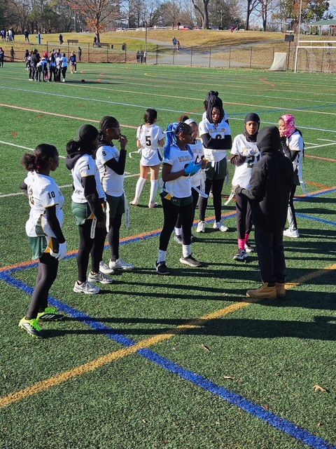 A girls' sports team gathered together on a playing field