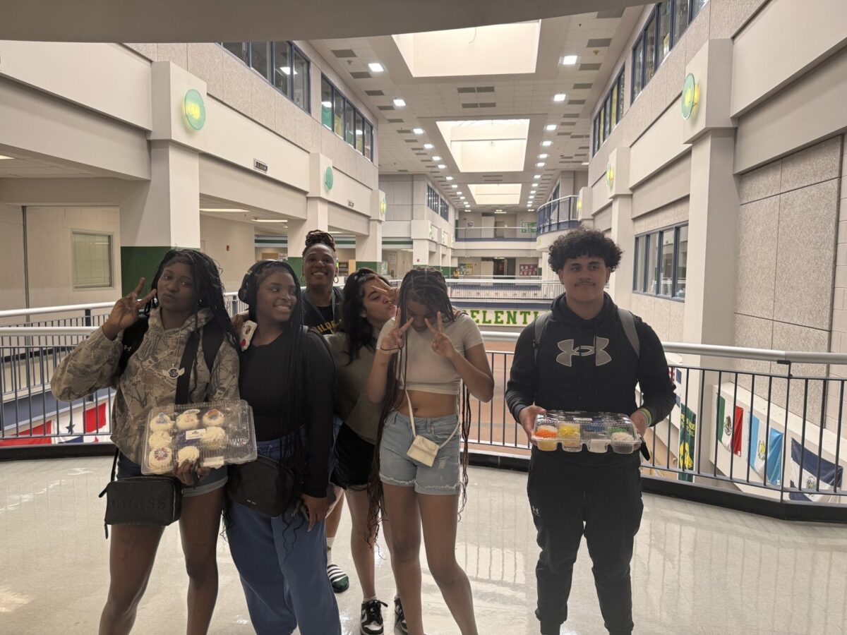 Five Wilde Lake students in the school atrium, holding trays of cupcakes they brought to the club meeting
