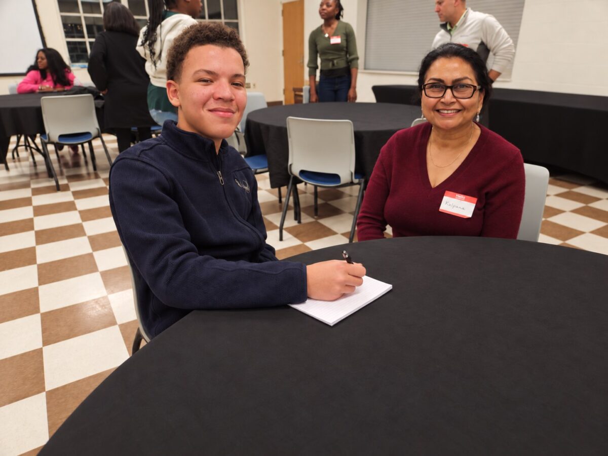 An OhanaHC student and a mentor smiling together at a table during a mentor and student meet and greet.