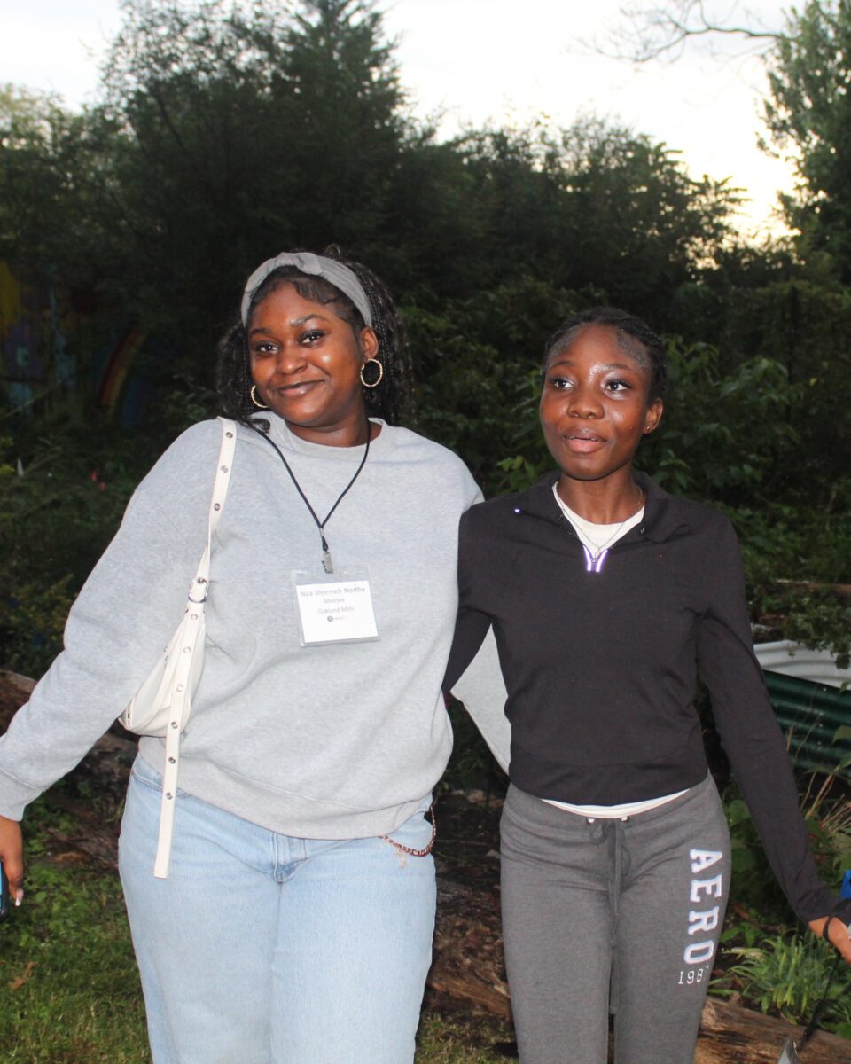 Two OhanaHC students smiling side by side in the garden at the fall bonfire