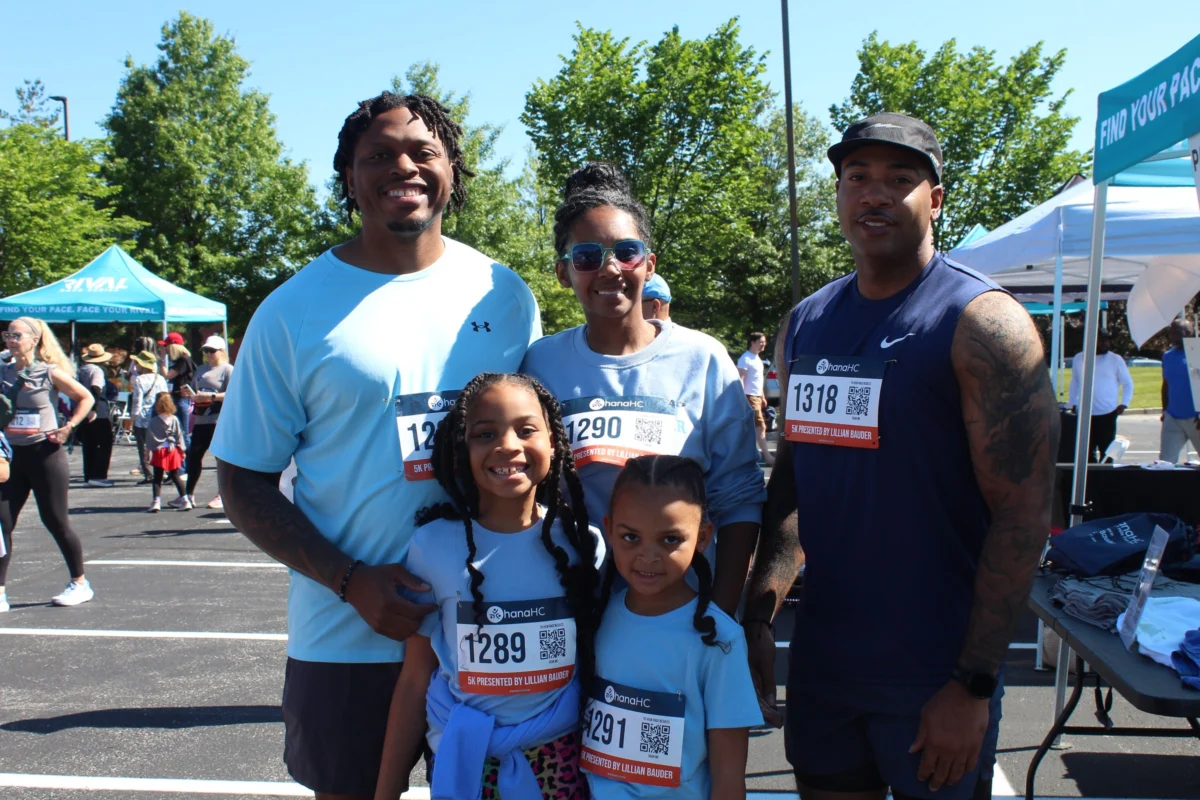 A family of five in OhanaHC race shirts and bibs smiling together at the Ohana 5K