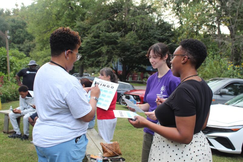 OhanaHC mentors and students playing bingo together on the lawn at a summer gathering