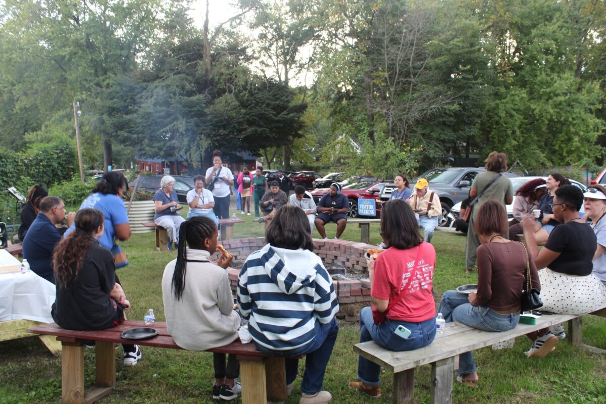 OhanaHC students, mentors and families seated on benches around the fire ring at the fall bonfire